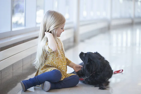 Joyeux petite fille assise sur le sol et jouant avec chien noir — Photo