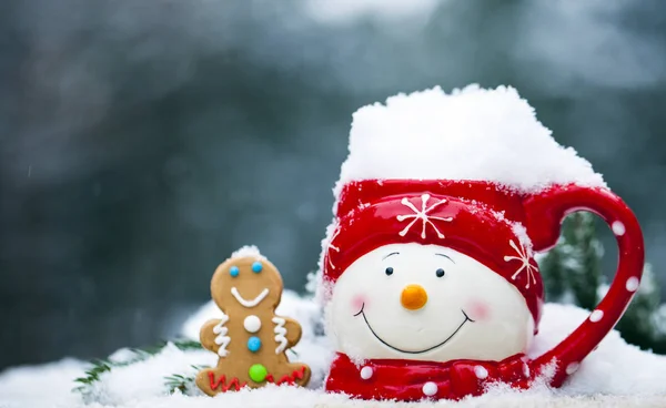 Zbliżenie: kubek z snowman twarz pełne śniegu i Piernik — Zdjęcie stockowe