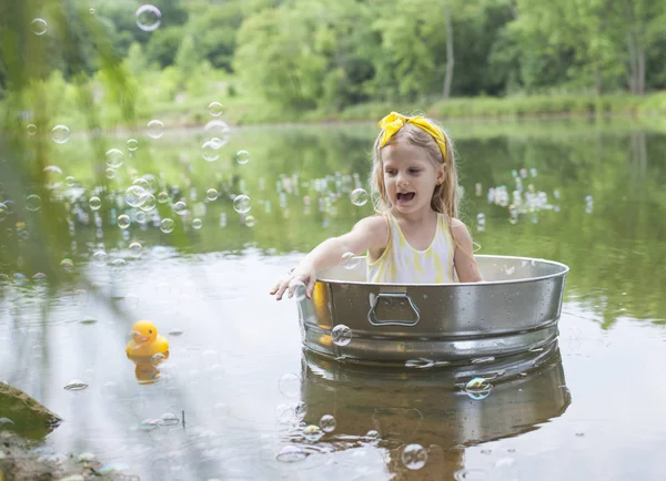 Menina feliz jogando na banheira de metal no lago no verão — Fotografia de Stock