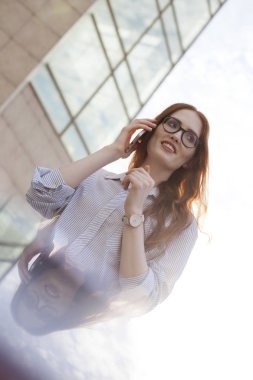 Mutlu genç bayan yönetici veya öğrenci cep telefonuyla konuşuyor.