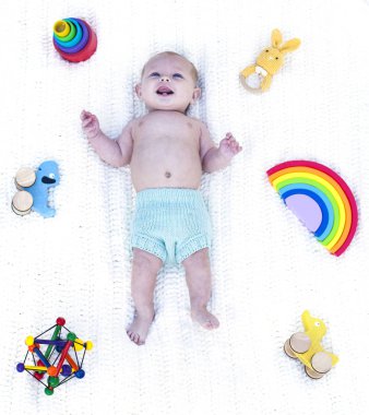 Küçük komik çocuk beşikte oyuncaklarla yatıyor.