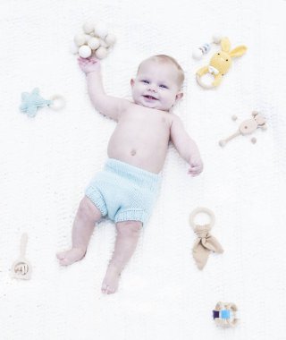 Gülümseyen bebek battaniyeye uzanmış sert bir oyuncak