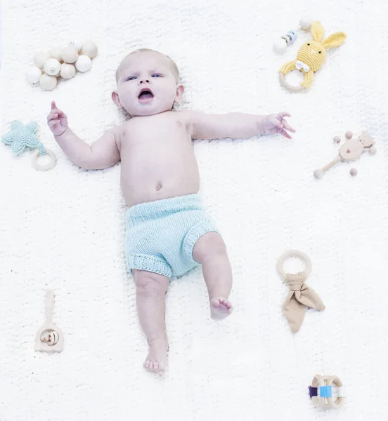 Portrait of displeased little baby lying on blanket with toys — Stock Photo, Image