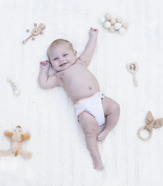 Feliz niño pequeño estirándose sobre una manta entre juguetes — Foto de Stock