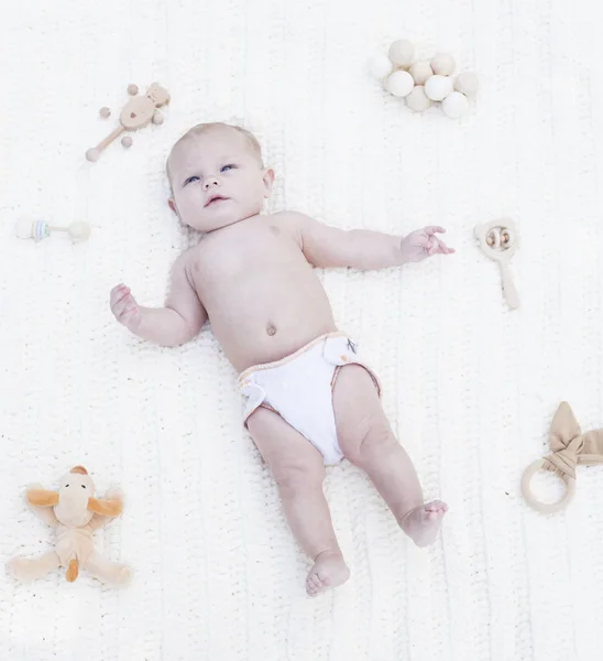 Retrato de bebé tranquilo acostado en pañal con juguetes — Foto de Stock