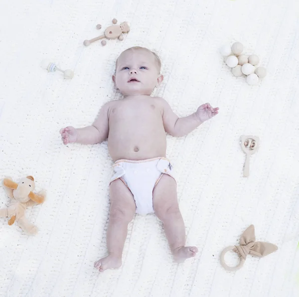 Retrato de bebé tranquilo descansando en la cama con juguetes — Foto de Stock
