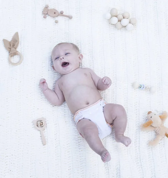 Retrato de lindo bebé bostezando en la cama entre juguetes — Foto de Stock