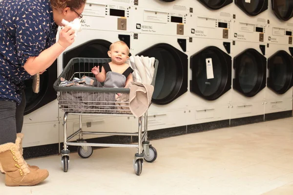 Mor med lille son i vagnen lägger linne i tvättmaskin — Stockfoto