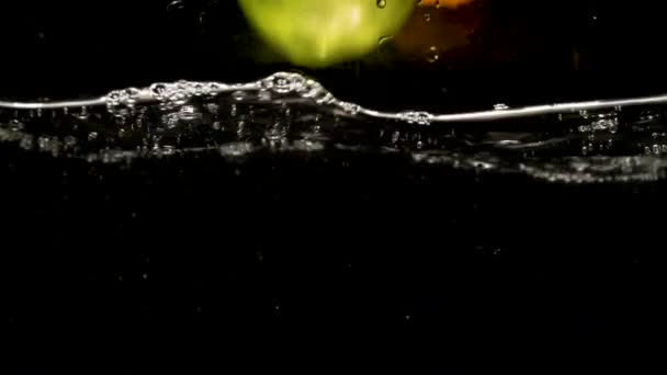 Een Groene Appel Twee Sinaasappelen Water Vallen Slow Motion Video — Stockvideo