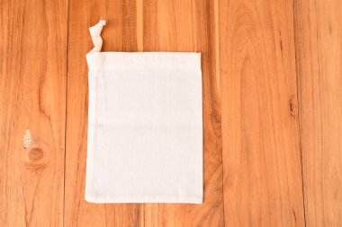 Ahşap arka plan üzerinde plastik atık hızı azaltmak için bez torba.