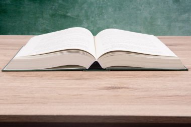 Bir kara tahta ahşap masa zemin üzerinde açık kitaptır.