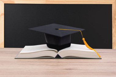 Siyah kitap üzerine yerleştirilen mezun Püskül kap.