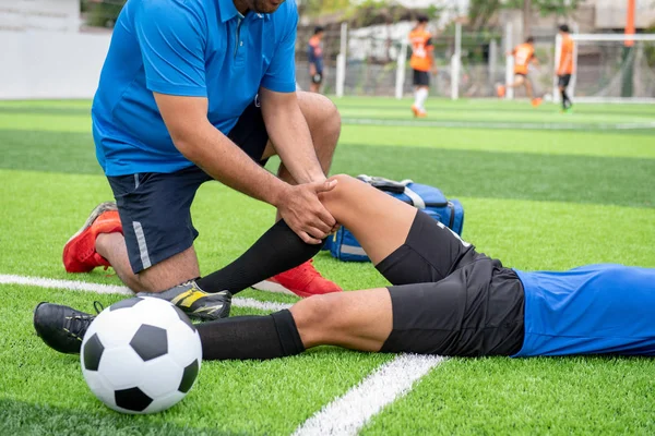 Mavi bir gömlek, siyah pantolon içinde çim yarış sırasında yaralı giyen futbolcu.