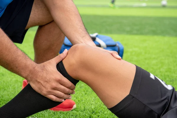 Mavi bir gömlek, siyah pantolon içinde çim yarış sırasında yaralı giyen futbolcu.