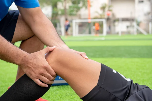 Mavi bir gömlek, siyah pantolon içinde çim yarış sırasında yaralı giyen futbolcu.