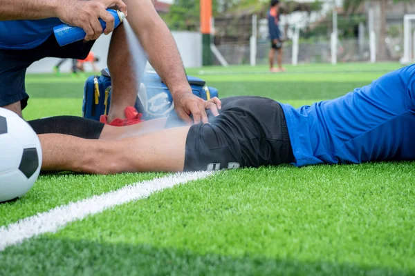 Mavi bir gömlek, siyah pantolon içinde çim yarış sırasında yaralı giyen futbolcu.