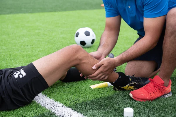 Mavi bir gömlek, siyah pantolon içinde çim yarış sırasında yaralı giyen futbolcu.
