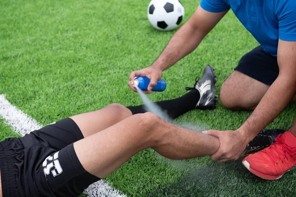Mavi bir gömlek, siyah pantolon içinde çim yarış sırasında yaralı giyen futbolcu.