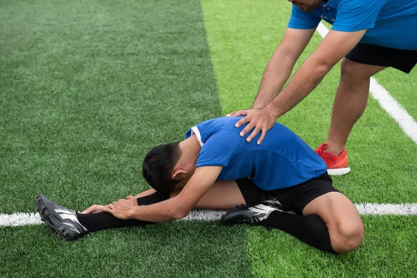 Mavi bir gömlek, siyah pantolon içinde çim yarış sırasında yaralı giyen futbolcu.