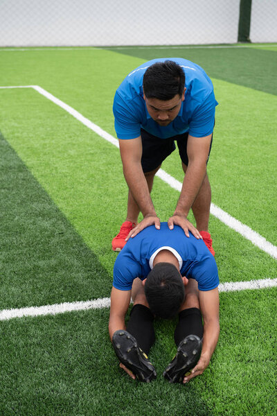 Footballer wearing a blue shirt, black pants injured in the lawn during the race.