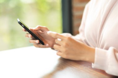 Kafe alışverişinde cep telefonuyla ameliyat maskesi takan bir kadın.