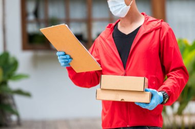 Teslimatçı, kırmızı eldiven giymiş, elinde karton kutu tutan, kırmızı eldiven giyen, elinde karton kutular tutan mavi eldivenli bir adam.