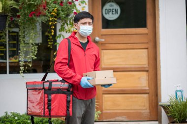 Teslimatçı, kırmızı eldiven giymiş, elinde bir paket var.