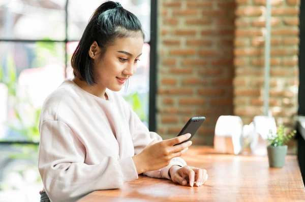 Kafe alışverişinde cep telefonuyla ameliyat maskesi takan bir kadın.