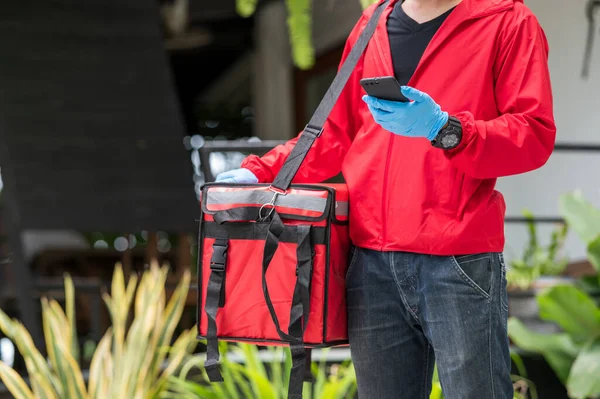 teslimatçı kırmızı bez. Cep telefonuyla müşteri adresi aranıyor.