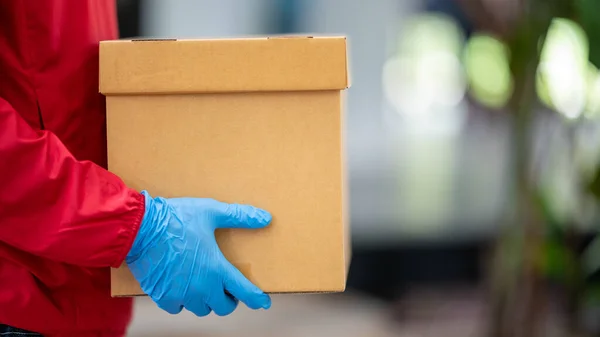Close Dostawca Niebieskich Rękawiczkach Czerwonej Tkaninie Trzymając Opakowanie Pudełka — Zdjęcie stockowe