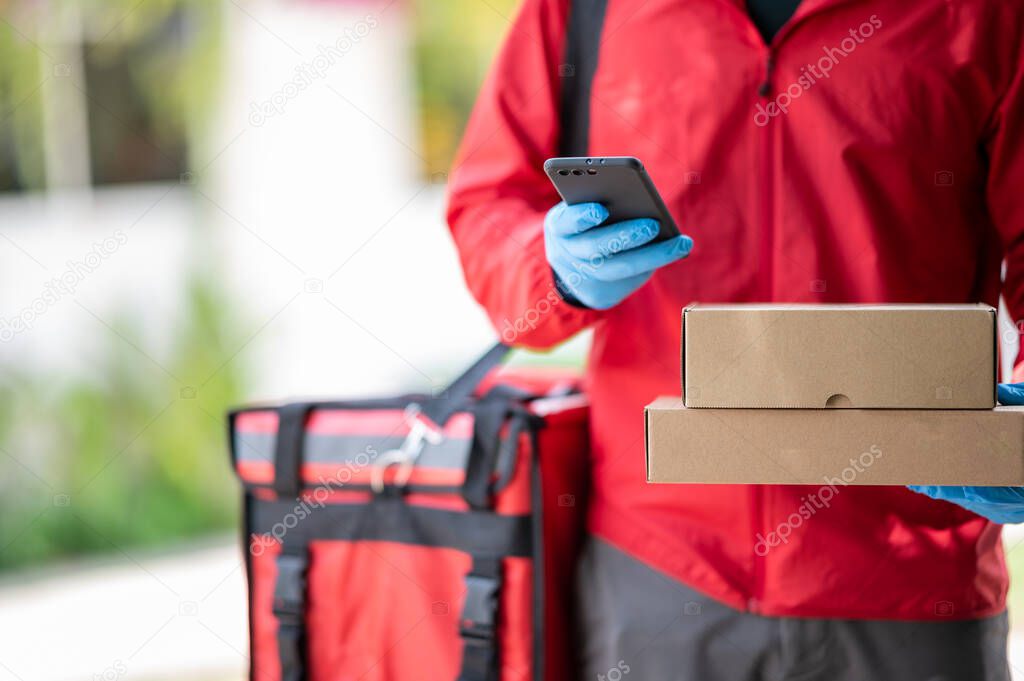Close up delivery man Wearing blue gloves in red cloth Searching for customer address by mobile phone