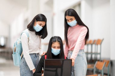 Bir grup kız öğrenci üniversitede verilerini dizüstü bilgisayarla çizmiş.