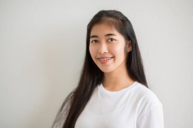 Asyalı bir kız üniversite öğrencisi üniversiteye gülümsedi ve kameraya baktı..