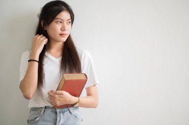 Asyalı bir kız üniversite öğrencisi üniversiteye gülümsedi ve kameraya baktı..