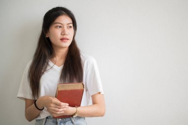 Asyalı bir kız üniversite öğrencisi üniversiteye gülümsedi ve kameraya baktı..