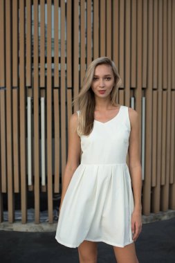 Sarışın kız kahverengi duvarın yanında ayakta