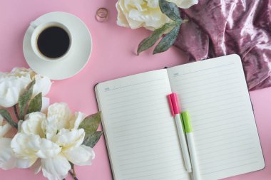 Bir fincan kahve ve çiçekli pembe arka plan üstünde defter