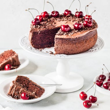 Dilimlenmiş çikolatalı pasta Çikolata talaşı ve tatlı kirazla süslenmiş, kare.