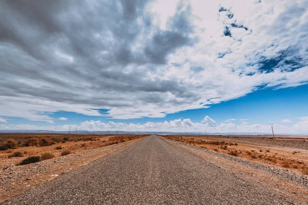 Çöl yolu Atlas Dağları ve tizi n Ouaaraben Pass, bulutlu bir gökyüzü altında gidiyor. Fas 'ın güneyinde
