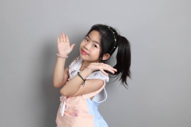 Gri arka planda duran, süslü giyinmiş Asyalı küçük kız..