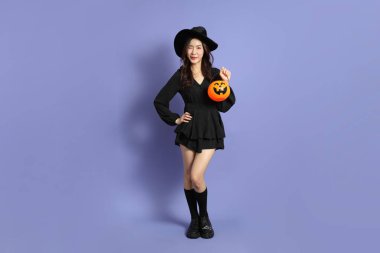 Cadılar Bayramı kostümlü güzel Doğu Asyalı kadın menekşe arka planda duruyor..