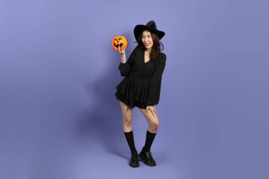 Cadılar Bayramı kostümlü güzel Doğu Asyalı kadın menekşe arka planda duruyor..