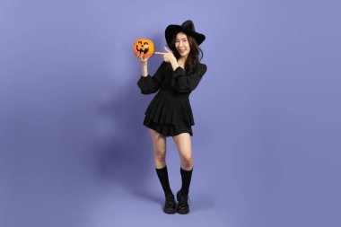 Cadılar Bayramı kostümlü güzel Doğu Asyalı kadın menekşe arka planda duruyor..