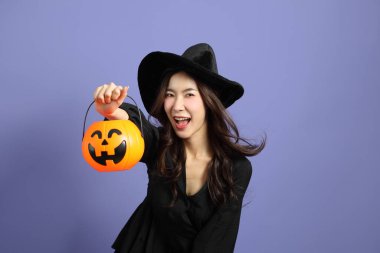 Cadılar Bayramı kostümlü güzel Doğu Asyalı kadın menekşe arka planda duruyor..