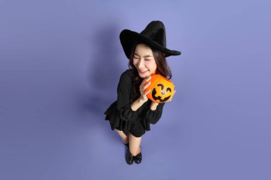 Cadılar Bayramı kostümlü güzel Doğu Asyalı kadın menekşe arka planda duruyor..