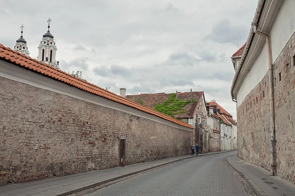 Hidden Old town street of Vilnius, Lituania. Paredes de edificios medievales, techos de azulejos. Iglesia de Santa Catalina campanarios. Europa atracciones turísticas, viajes . — Foto de Stock