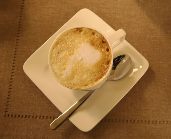 Чашка капучино на бежевой скатерти из коричневого льна. Кафе, кофе-брейк, кофейня, завтрак, ресторан, меню, подъем, плоская постель. Ностальгическая ретро-атмосфера . — стоковое фото