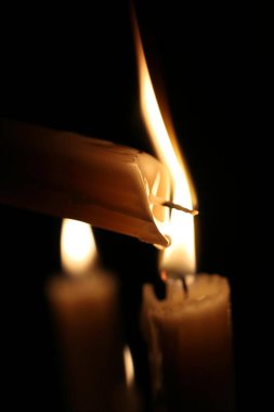 Karanlıkta bir mum ışığı, erimiş mum, alevler bırakır. Yakın çekim. Noel, yeni yıl tebrik kartı, tüm azizler günü, tüm toplantı salonu Eve, kilise, din, inanç, dua, tatil, kış masal.