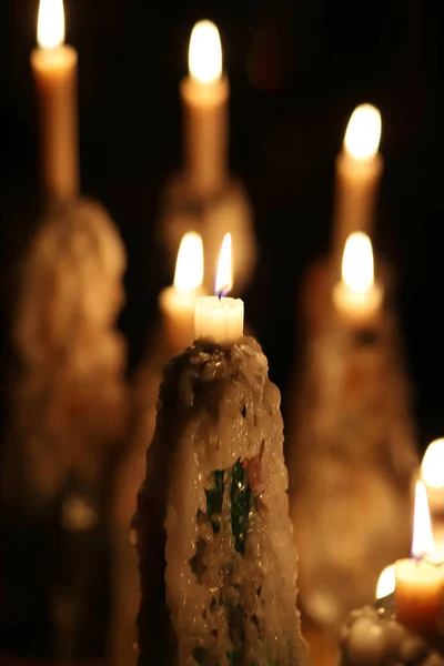 Brandende kaarsen in de donkere, gesmolten kaarsvet, kaarsvlam. Kerstmis, Nieuwjaar wenskaart, Allerheiligen, All Hallows Eve, kerk, godsdienst, geloof, vakantie, magische, winter fairy tale. — Stockfoto