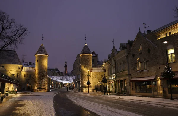 Tallin, Estonia - 7 de enero de 2019: vista de las puertas del casco antiguo con torres de castillo y un Ayuntamiento en invierno a la hora azul. Europa atracción turística . — Foto de Stock